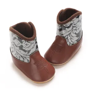 Detailed view of baby winter boots with brown faux leather and silver glitter patterns