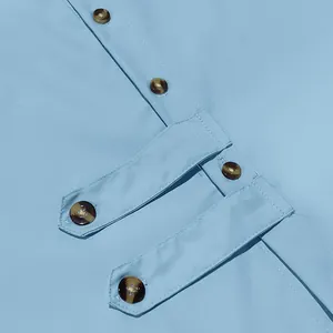 Détail des boutons décoratifs et de la patte sur une chemise décontractée bleu clair