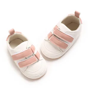 Detail von weißen und rosa PU-Leder Babyschuhen mit weicher Sohle und Klettverschluss.