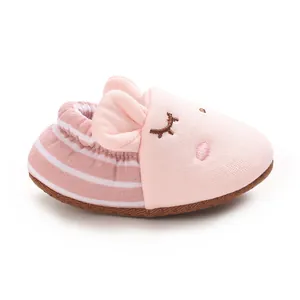 Primo piano di una pantofolina rosa per neonati con ricamo viso di animale e strisce
