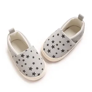 Vista dettagliata di scarpe primi passi grigie per neonato con stelle e suola morbida.