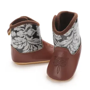 Close-up view of brown baby winter boots featuring silver floral patterns and soft fur lining