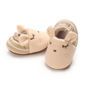 Vista dettagliata di scarpine in tessuto beige per neonati con simpatico musetto di animale
