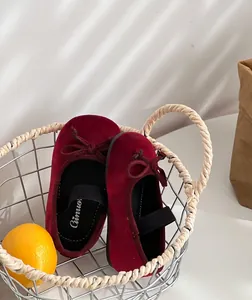 Detailed view of wine red velvet girls' princess shoes with bow accents in a basket