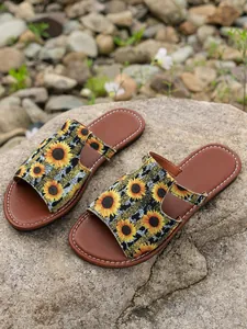 Dames slippers met zonnebloemprint in etnische stijl op een natuurlijke stenen achtergrond