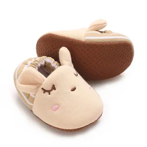 Dettaglio di scarpine neonato beige con viso di animale carino e suole antiscivolo