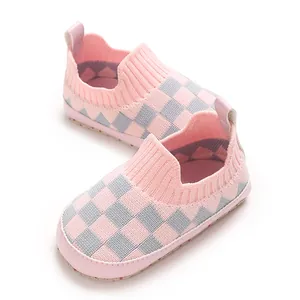 Primer plano de zapatos de bebé de punto a cuadros rosa y gris con suelas suaves