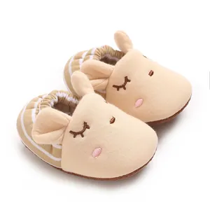 Primo piano di adorabili pantofole da neonato a forma di coniglio beige con righe