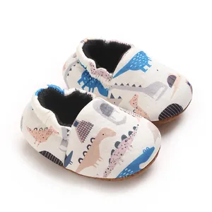 Primo piano di scarpine in cotone per neonati con motivi colorati di dinosauri, 0-1 anno.