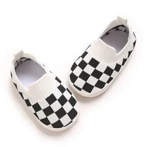 Vista superior de zapatos de punto para bebé con patrón de cuadros blancos y negros.