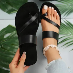Detail view of black flat toe-loop sandals with stylish leather straps for summer beach.