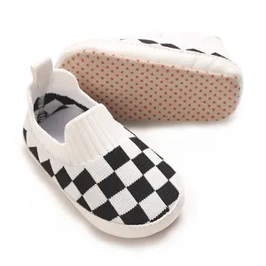 Detalle de zapatos de punto para bebé con diseño de tablero y suela antideslizante