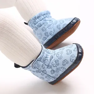 Nahaufnahme von hellblauen Baby-Schneestiefeln mit Auto-Cartoon-Muster am Babybein