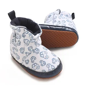 Nahaufnahme weißer Babystiefel mit blauem Automuster und einer weichen braunen Rutschsohle.