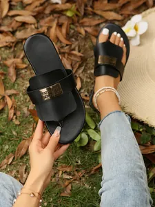 Nahaufnahme der schwarzen Zehensandalen für Damen mit dekorativer Metallplatte