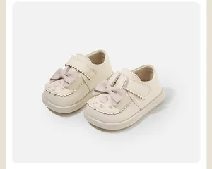 Adorable cream baby shoes with decorative rabbit ears and pink bows detail.