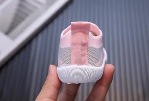 Dettaglio scarpa primi passi neonato in maglia rosa e grigia con suola morbida
