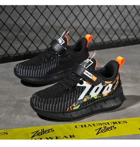 Close-up detail of black breathable mesh boys' running shoes with orange accents.