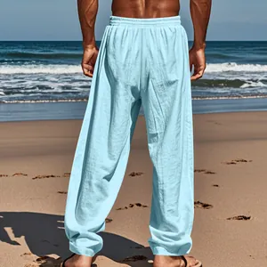 Detailed rear view of light blue men's loose cotton linen casual pants on a sunny beach