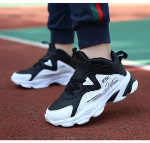 Vue détaillée de baskets imperméables pour garçons en noir et blanc sur piste de sport.