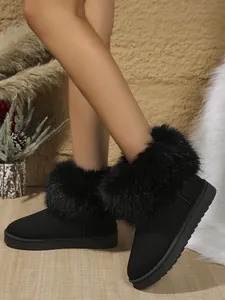 Gros plan de bottes de neige noires avec garniture en fourrure de renard sur les jambes