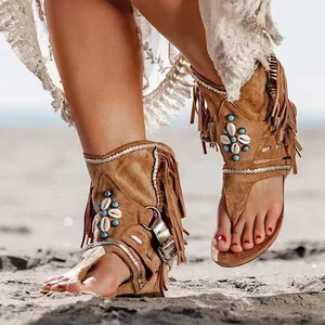 Vista detallada de sandalias planas bohemias con flecos, cuentas turquesas y conchas