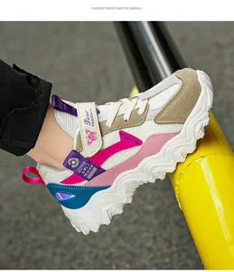 Detailansicht der weißen und rosa klobigen Sportschuhe für Mädchen an einem gelben Poller