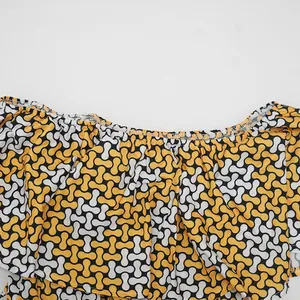 Primer plano de vestido con estampado geométrico amarillo y blanco y escote volantes.