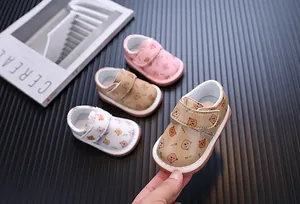 Dettaglio di scarpe per neonati con suola morbida e motivi a orsetto in vari colori
