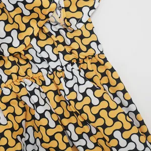 Primer plano detallado del patrón geométrico y la cintura elástica del vestido amarillo