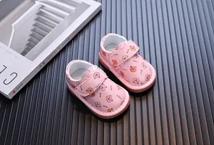 Dettaglio ravvicinato di scarpe primi passi rosa con motivo a orsetto e chiusura a strappo.