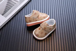 Dettaglio delle scarpe da neonato kaki con un motivo a orsetto e la suola morbida.