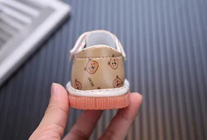 Primo piano di scarpe primi passi per neonati con motivo a orsetto e suola rosa