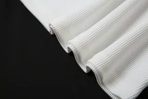 Dettaglio macro della trama del tessuto a coste bianco e dell'orlo di questo set casual