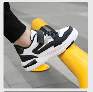 Vue de profil de baskets en cuir noir et blanc pour enfants avec bride velcro