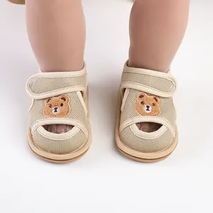 Nahaufnahme der Bärenstickerei und atmungsaktiven Mesh-Textur auf Babysandalen.