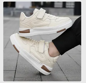 Détail de baskets blanches pour enfants en similicuir avec velcro sur sol extérieur.