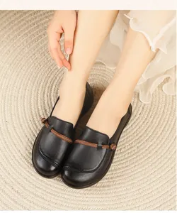 Detailansicht der schwarzen flachen Leder-Loafer mit braunem dekorativem Knotendetail