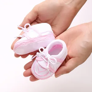 Vue détaillée de chaussettes de sol roses pour bébé avec un nœud, tenues à la main