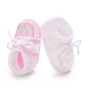 Détail en gros plan de chaussettes bébé blanches avec broderie cœur rose et un nœud