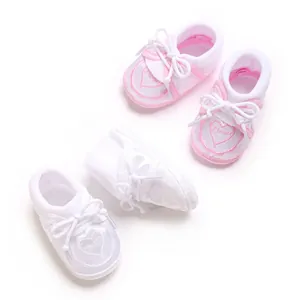 Gros plan de chaussettes de sol douces pour bébé avec broderie cœur et lacets noeud.