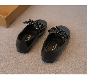 Detailansicht schwarzer Lacklederschuhe für Mädchen mit Schleife und Goldmarkierung.