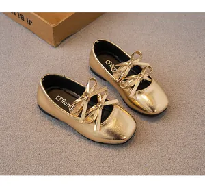 Detailansicht der Doppelschleifen und der goldenen Textur dieser Mädchenschuhe.