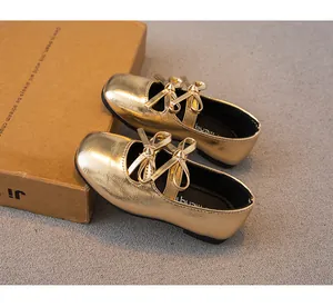 Nahaufnahme goldener Mädchen-Mary-Jane-Schuhe mit doppelter Schleife