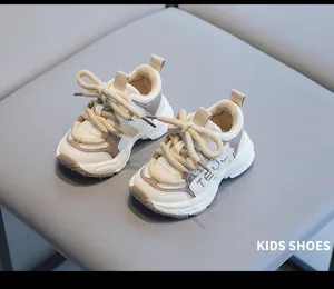Detailed view of cream and taupe chunky sneakers for toddlers on a grey background