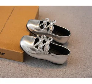Nahaufnahme von silbernen Prinzessinnenschuhen für Mädchen mit Schleifen und Metallic-Finish