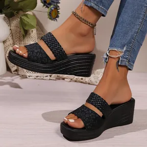 Detail view of black wedge sandals featuring braided and leopard print straps on feet.