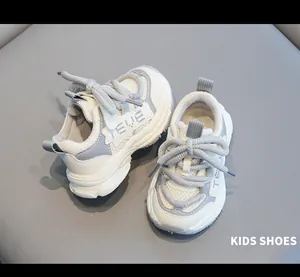 Detailed view of white and grey kids' sneakers with chunky soles and thick laces.