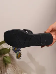 Detailed view of black woven wedge slipper sole with non-slip texture pattern