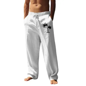 Close-up detail of men's loose white cotton linen pants featuring a black palm tree print